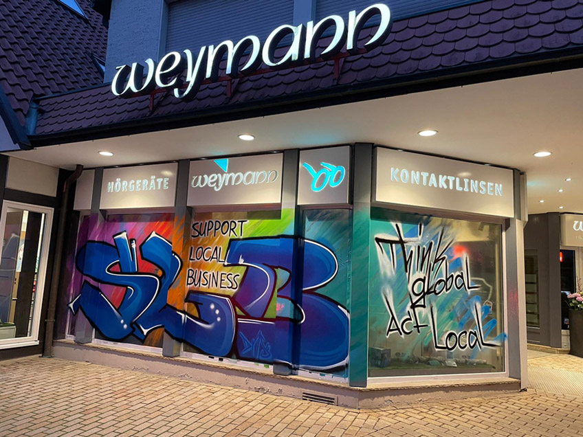 Seit gestern prangt an der Schaufensterfront vom Zentrum f&uuml;r Seh- und H&ouml;rberatung Weymann in L&uuml;bbecke ein farbenfrohes Graffiti. Mit dieser au&szlig;ergew&ouml;hnlichen Idee m&ouml;chte sich Firmenchef J&ouml;rg Weymann bei der L&uuml;bbecker Bev&ouml;lkerung f&uuml;r die Treue w&auml;hrend der Corona-Zeit bedanken.