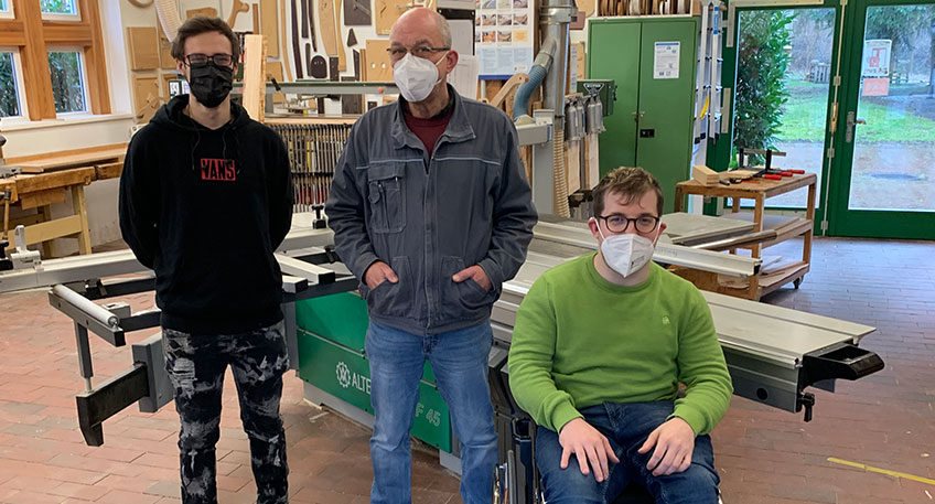 Junggeselle Dennis Koring (links) freut sich zusammen mit Ausbilder und Tischlermeister Frank Diekmann und (Mitte) und Sozialarbeiter Diakon Michael Biesewinkel (rechts) über seine abgeschlossene Ausbildung zum Tischler. Hier stehen alle in der Ausbildungswerkstatt des Büttemeyer Hofs der Ev. Stiftung Ludwig-Steil-Hof.