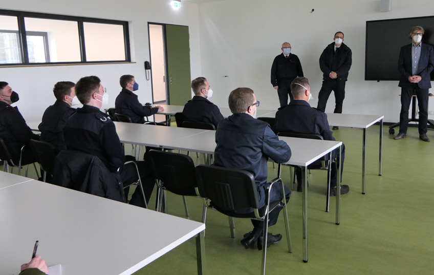 Aus einem Brandsimulationscontainer schießt Feuer von der Decke innen nach außen. Vor der Tür hocken zwei Brandmeisteranwärter aus Minden und Porta Westfalica in Schutzkleidung und warten darauf, in die „heiße Hölle“ zu stürmen.