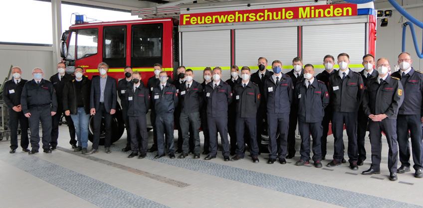 Aus einem Brandsimulationscontainer schießt Feuer von der Decke innen nach außen. Vor der Tür hocken zwei Brandmeisteranwärter aus Minden und Porta Westfalica in Schutzkleidung und warten darauf, in die „heiße Hölle“ zu stürmen.
