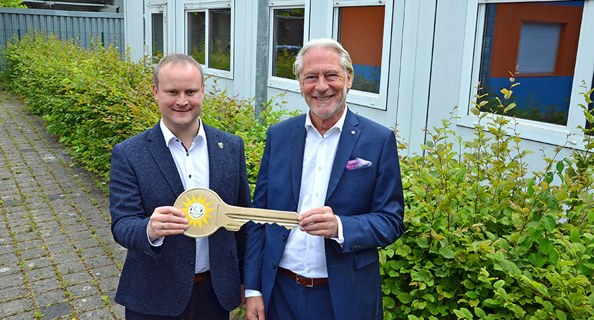 J&uuml;rgen St&uuml;hmeyer (rechts), Vorstand Merkur Vertrieb, &uuml;bergibt den symbolischen Schl&uuml;ssel f&uuml;r die Wohncontainer im Hintergrund an Espelkamps B&uuml;rgermeister Dr. Henning Vieker.